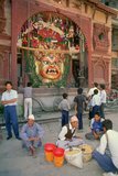 Rana Bahadur Shah installed the Shveta Bhairav (White Bhairav) in 1796 to drive away evil spirits and ghosts from Durbar Square. It represents the most terrifying form of the Hindu god Shiva.<br/><br/>

Just a few metres south of Kala Bhairav (Black Bhairav), the four metre high gilded, leering mask representing Shveta Bhairav is hidden behind a latticed wooden door. Compared to the boundless horror of Kala Bhairav, the almost charming wickedness of his nearby companion comes as a mild relief. The door in front of the mask is only opened during the festival of Indra Jatra. For the rest of the year it remains closed, hiding what is undoubtedly a more artistically executed figure than that of the Kala Bhairav.<br/><br/>

Despite greeting the visitor with an evil, tongueless grin, exposing long white teeth, the mask is leant a certain attractiveness by its golden hue. During Indra Jatra, copious amounts of rice beer are poured through the mouth of Shveta Bhairav, to be eagerly lapped up by the exuberant, jostling crowd.