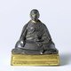 China / Tibet: Seated monk holding a lotus, silver with gilt base, 17th century