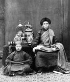 This photograph by Thomas Child, titled Mongolian Lama, is one of the earliest photographic portraits of a religious figure in Peking (Beijing). In the 19th century, the term lama referred to any Tibetan Buddhist monk or teacher.<br/><br/>

The lama and his pupil both hold prayer beads and bundles of sutras in their laps. Displayed neatly on the table are bronze sculptures and sacred Tibetan ritual objects including a skull cup.