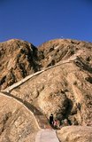 Located about 7km northeast of Korla, the ancient strongpoint of Tiemenguan or 'Iron Gate' is set amid incredibly barren, harsh and crumbling mountains. It’s possible to understand the immense strategic significance of the ‘Iron Gate’ pass by climbing the 1,497 steps to the summit.<br/><br/>

Here the tomb of the lovers Tzuhola and Tayir is set high above the narrow defile that once channelled the old Silk Road between two massive and impassable rocky outcrops. A small path winds by a stream, far below – nowadays all but unused, but for at least two millennia a narrow artery for men, good and camels passing between east and west.<br/><br/>

Because of its strategic location controlling the Silk Road as it passed south of the Tian Shan and into the Tarim Basin, Tiemenguan was easily defended by garrison troops and almost impossible for merchants and other travellers to avoid.<br/><br/>

For Uighurs the narrow pass is associated with tragedy in love. Long ago Tzuhola, a Uighur princess, fell in love with Tayir, a simple shepherd. Her father, the king, had intended the princess to marry a prince, and was greatly displeased. The two lovers fled into the mountains pursued by the king’s troops, who had orders to bring them back. They fell to their deaths near Tiemenguan and the king, who was heartbroken, ordered the building of a twin tomb so they could be together in the afterlife. A statue of the two lovers in flight on horseback has recently been erected near the tomb.