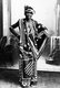 Tanzania / Zanzibar: Fashionably dressed young woman of the Swahili Coast wearing dress decorated with crossed elephant tusks. A.C. Gomes and Co.Zanzibar, c. 1900