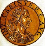 Carinus (-285) was Emperor Carus' eldest son, and was appointed Caesar in the beginning of 283, made co-emperor of the western portion of the Roman Empire while his father and younger brother Numerian headest eastwards to fight the Sassanid Empire.<br/><br/>

When his father died in mid-283, Carinus and Numerian became co-emperors of the Empire, with Carinus swiftly returning to Rome to celebrate his ascension. In 284, Numerian was found dead in his closed coach under mysterious circumstances, with Diocletian, commander of Numerian's bodyguards, claiming that Numerian had been assassinated. Diocletian was almost immediately proclaimed emperor by his soldiers, and Carinus was forced to march and face him.<br/><br/>

The two armies clashed in 285, with differing accounts on what occurred. One acount claims that Carinus' forces were winning, but the emperor was assassinated by a jealous tribune whose wife Carinus had seduced. A more believable account claims that Diocletian's troops secured a complete victory, and Carinus' army deserted him, leading to either his death by murder or execution. Carinus posthumously gained a reputation as one of the Empire's worst emperors, a slandering possibly supported by newly crowned Diocletian himself.