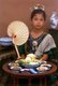 Thailand: A girl in traditional Lanna clothing with fan proffers a <i>khantoke</i> dinner, Chiang Mai, northern Thailand