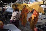 A woman receives blessings after offering money to monks on alms round in Kandal Market, Phnom Penh 2016.
